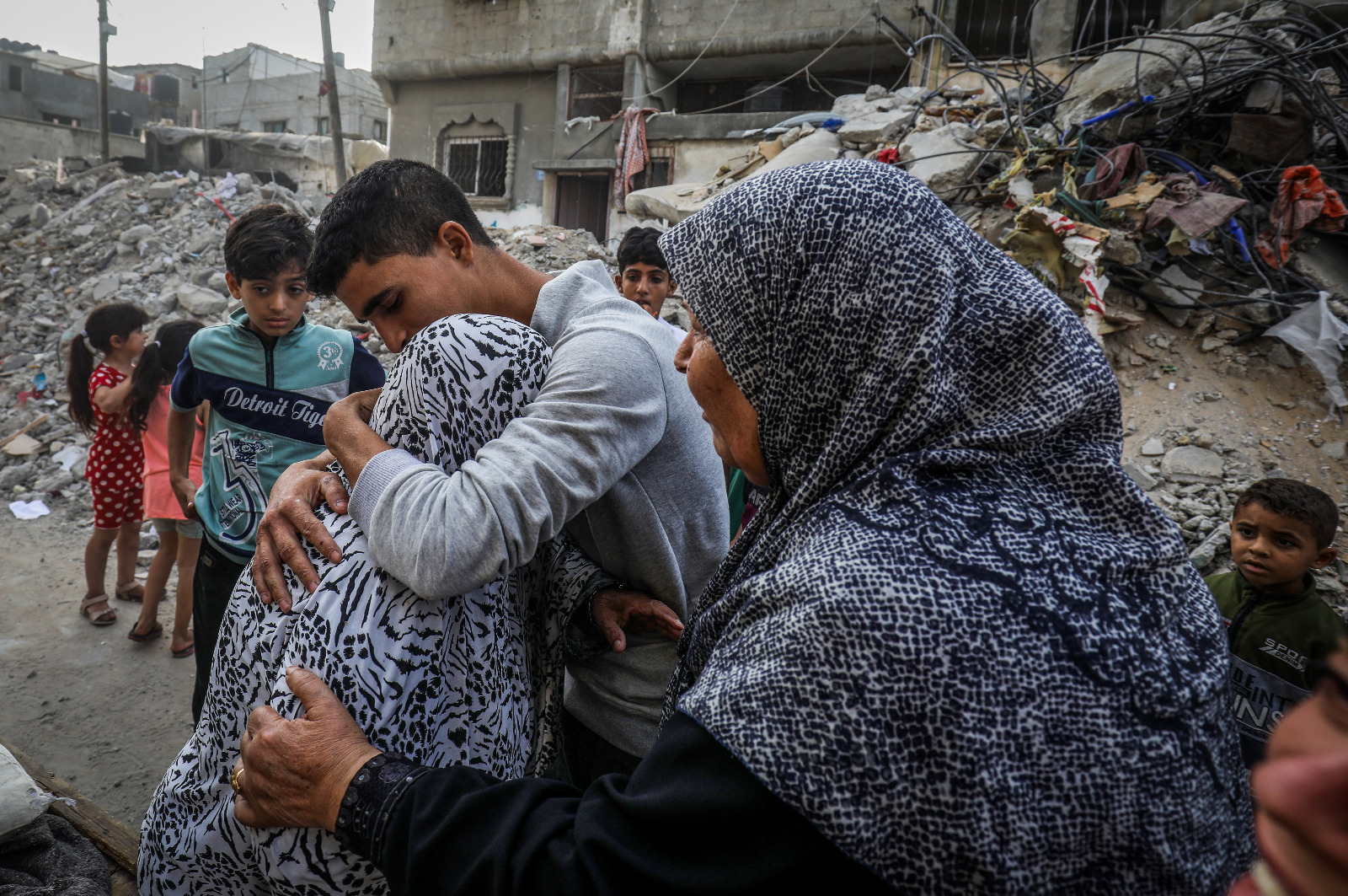 A family embraces amid the rubble of their neighborhood, holding on to each other and to hope