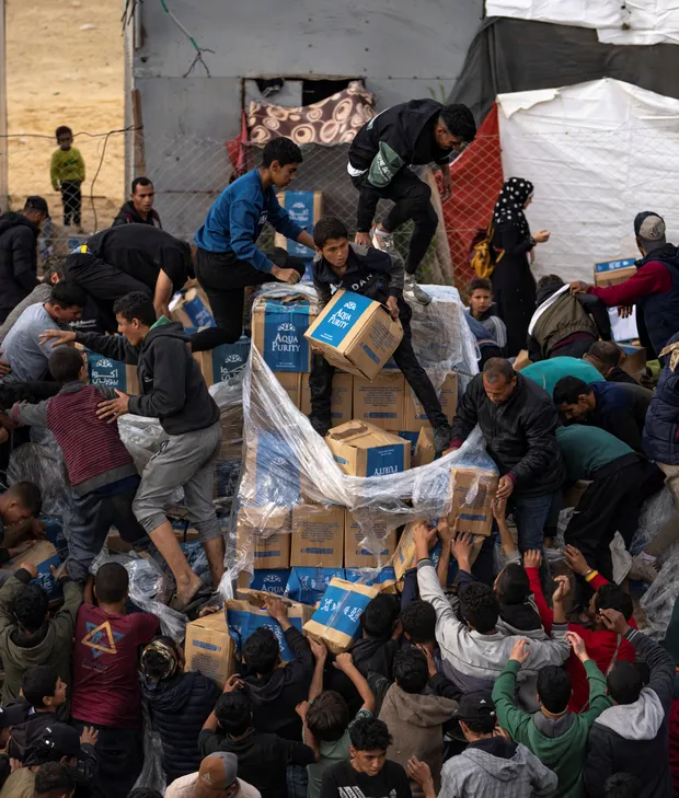 Families crowd around boxes of clean drinking water at a distribution point